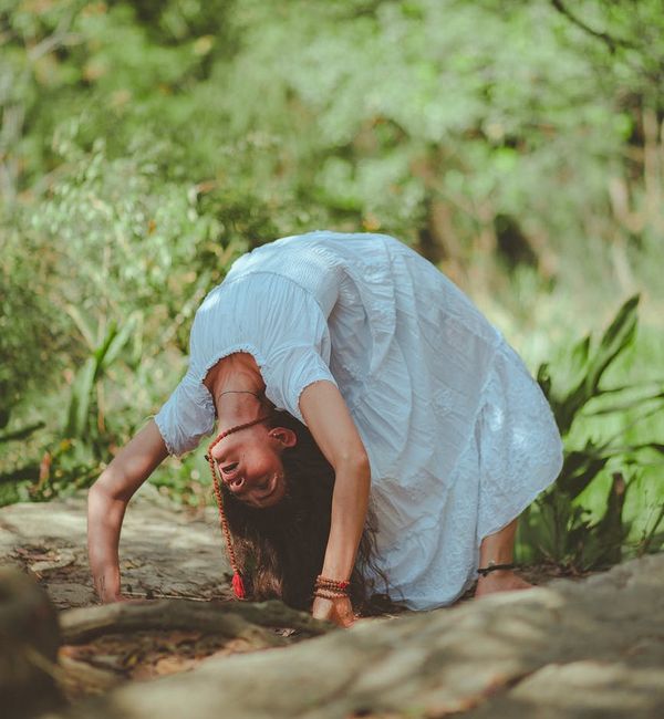Woman performing a deep hip-opening yoga stretch in a serene green environment.